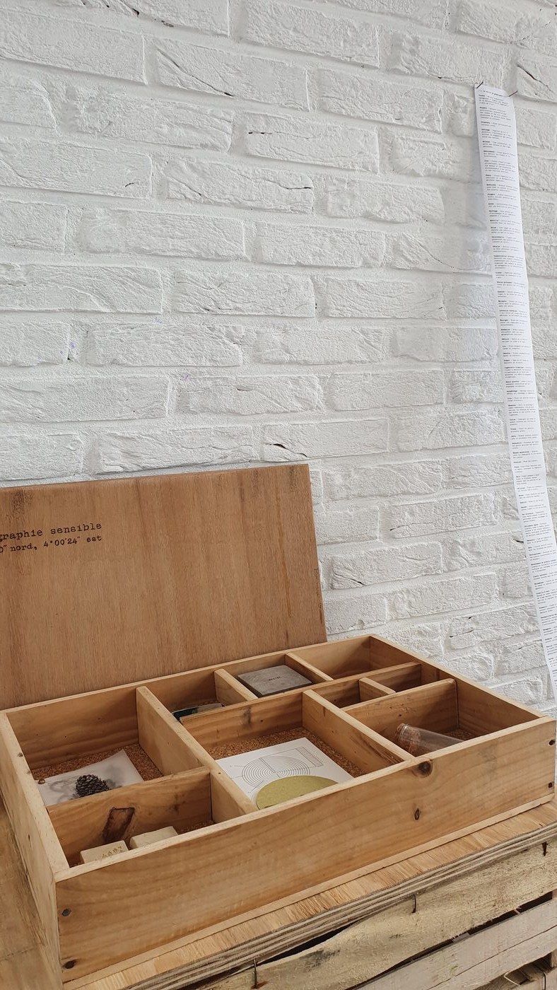 Cartographie sensible — la mallette en bois ouverte, compartiments avec cyanotypes et livrets.